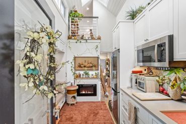 Compact modern kitchen with white cabinets and autumn decorations.
