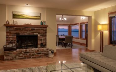 Cozy living room with brick fireplace and ocean view dining area.