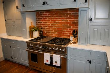 Modern kitchen with stainless steel stove and brick backsplash.