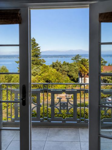 Scenic view of trees and water through open double doors.