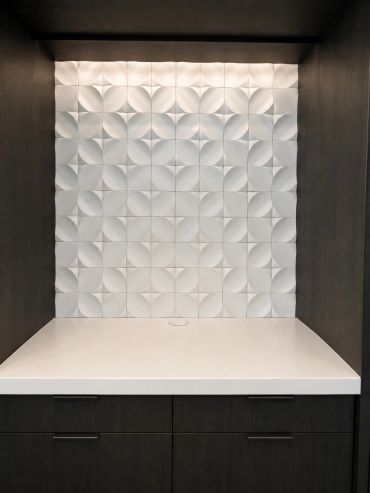 Modern kitchen backsplash with dark cabinetry and white geometric tiles.