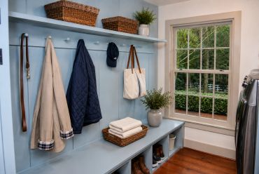 Neat mudroom with coats, basket, and window view.