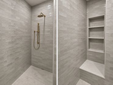 Minimalist shower with gray tiles and gold fixtures.