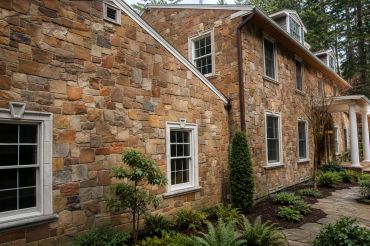 Stone-faced house exterior with windows and garden path.