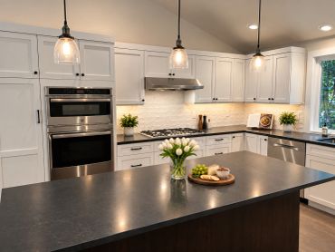 Modern kitchen with white cabinets and black countertops.