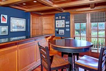 Cozy wooden bar and round table with chairs in a room.