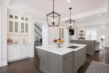 Modern kitchen with marble island and pendant lights.