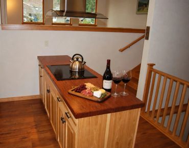 Wine, cheese, and snacks on a kitchen island with a kettle.