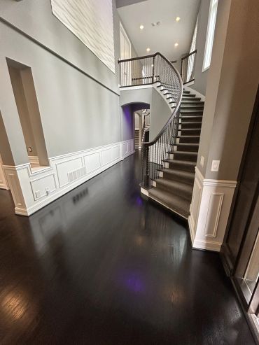 Elegant curved staircase with dark floors and gray walls.