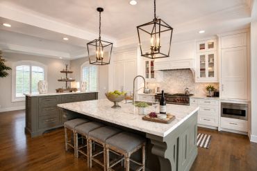 Bright kitchen with marble island and modern lighting.