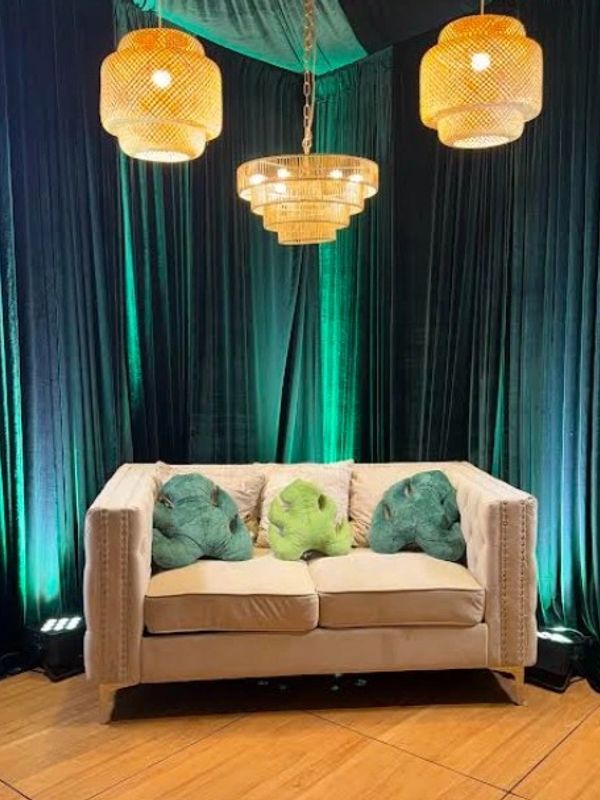 Cozy beige sofa with green and leaf-shaped pillows and warm lighting.