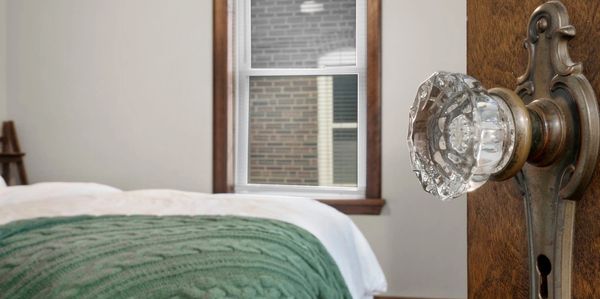 Door with original crystal door knob and door hardware leading into St. Louis home's bedroom