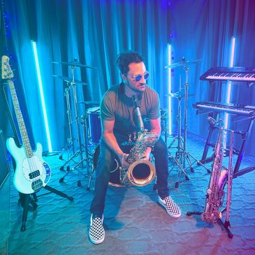 Man playing saxophone in a vibrant music studio with various instruments.