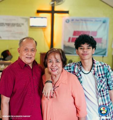 Three generations smile warmly inside a church with a cross in the background.