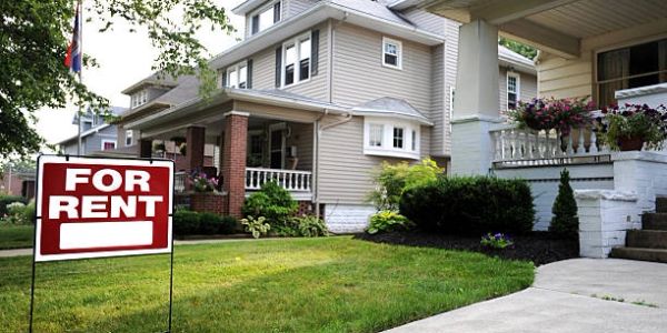 House with a for rent sign on the lawn.
