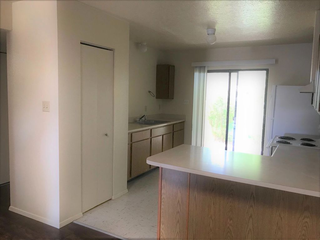 View of kitchen with more cabinets, pantry, and sliding glass door that opens to the backyard