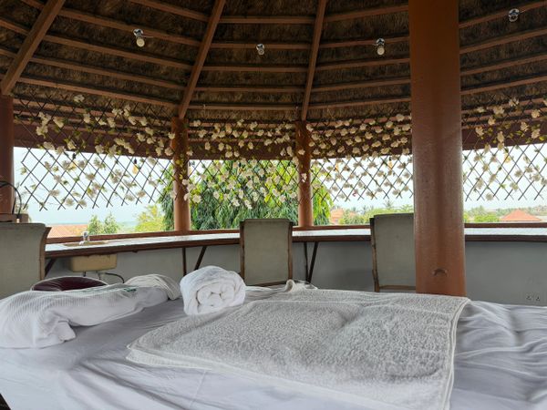 Cozy massage beds under a decorated gazebo with a scenic outdoor view.