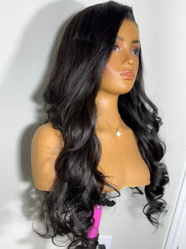 Mannequin head with long, wavy black hair and a gold necklace.