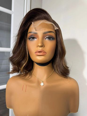 Mannequin head with styled brown wig and makeup, wearing a gold necklace.