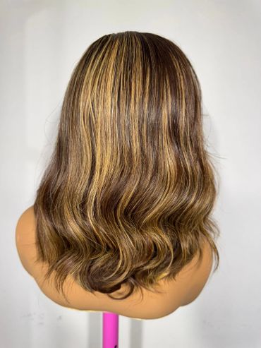 Back view of a mannequin head with wavy brown hair and blonde highlights.