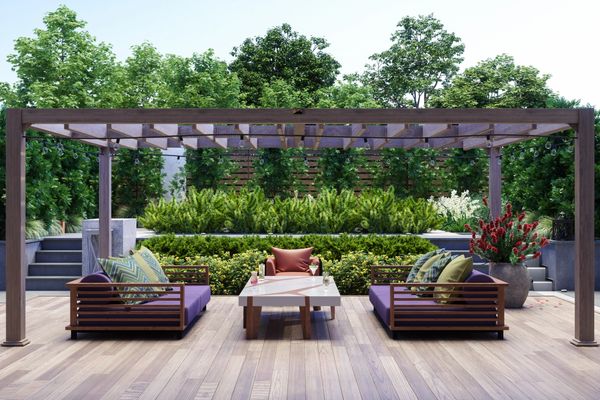 Outdoor patio with a pergola, two sofas, a table, and lush greenery in the background