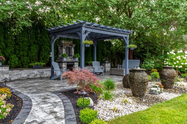 Outdoor patio with a grey pergola, fireplace, and water features.
