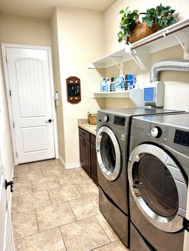 Modern laundry room with washer, dryer, and organized shelves.