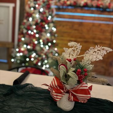 Festive Christmas centerpiece with red berries and striped bow on a decorated table.