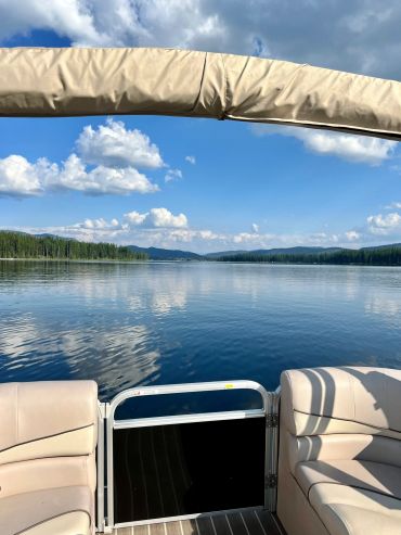 View from a pontoon boat of a calm lake with the sky reflecting off of it