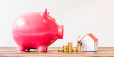 Pink piggy bank with coins and house model.