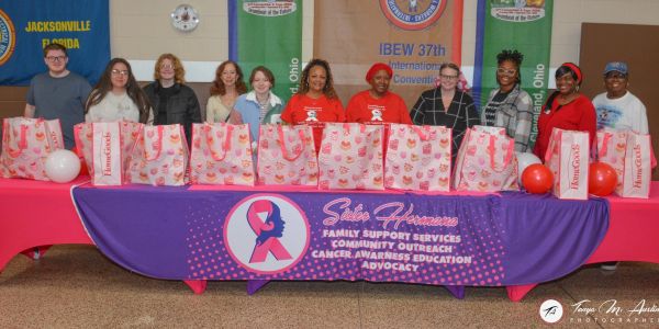 Group of people behind a charity table for cancer awareness.