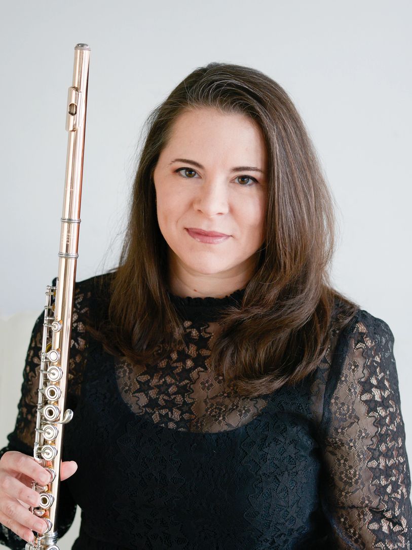 Woman holding a flute, wearing a black lace top.