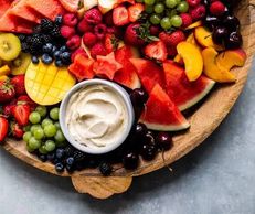 A vibrant fruit platter with cream dip in the center.