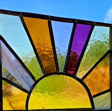 Stained glass panel of sun with light shining through.