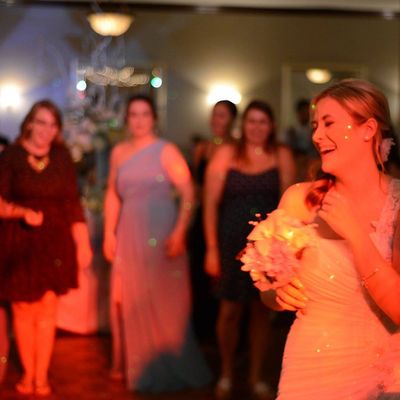 Youngstown DJ. Bride laughing while holding bouquet, guests in background ready for bouquet toss.