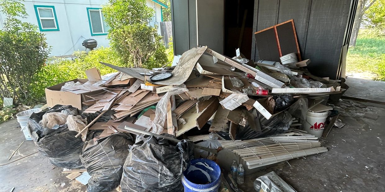 Pile of construction debris and garbage bags in a covered outdoor area.