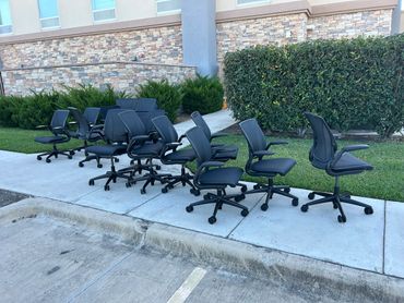 Black office chairs lined up on a sidewalk outside a building.