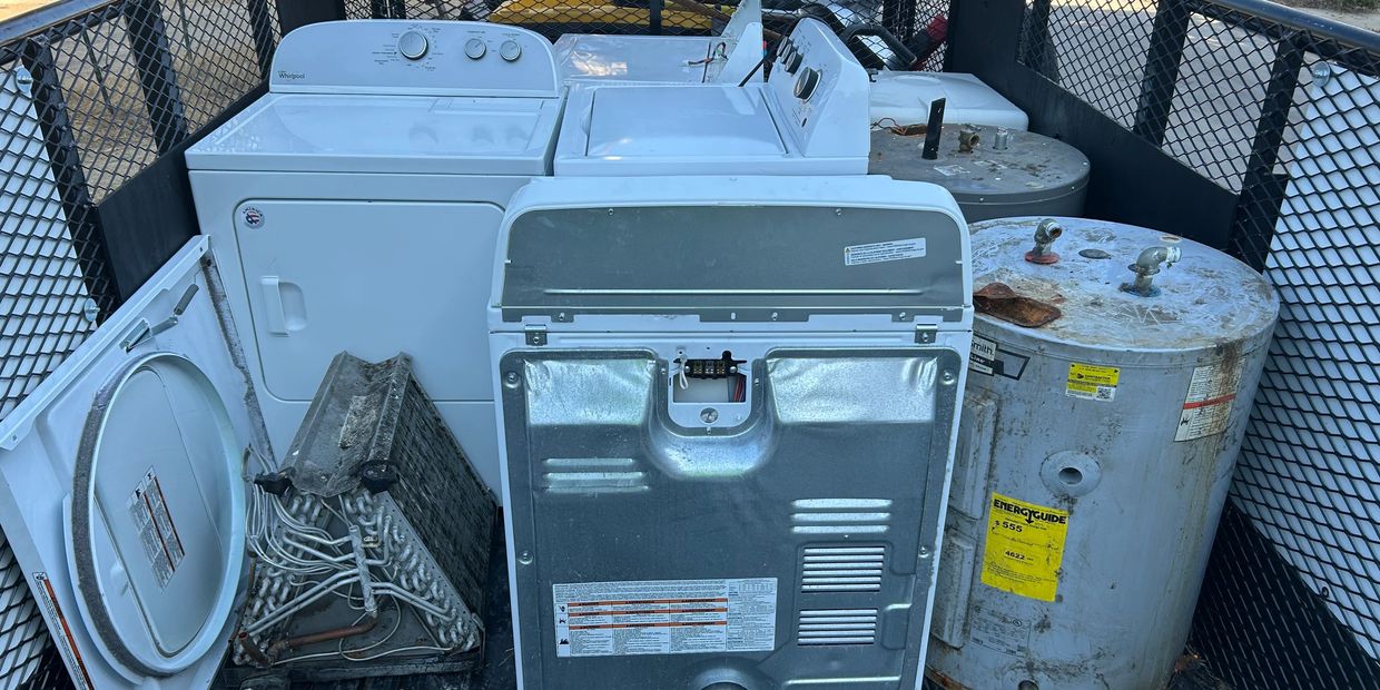 Old appliances and water heaters loaded in a trailer for disposal.