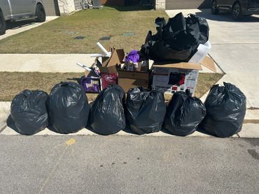 Seven black garbage bags and boxes are placed by the roadside for disposal.
