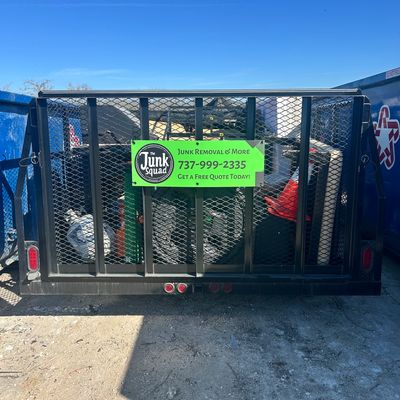 Trailer loaded with junk and a sign for The Junk Squad removal service.