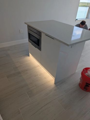 A lit kitchen island on a nice light wood floor