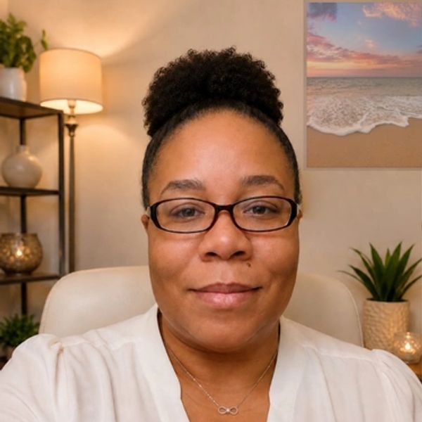 Woman smiling indoors with glasses and a high bun hairstyle.