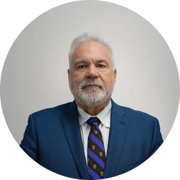 Mature man with white hair and beard in blue suit and patterned tie.