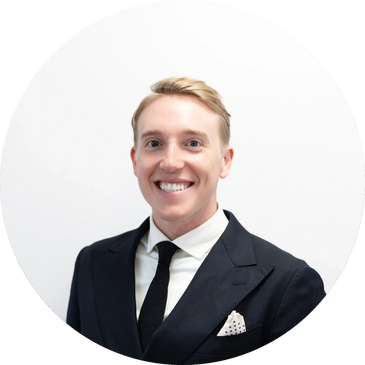 Smiling man in a black suit and tie against a white background.