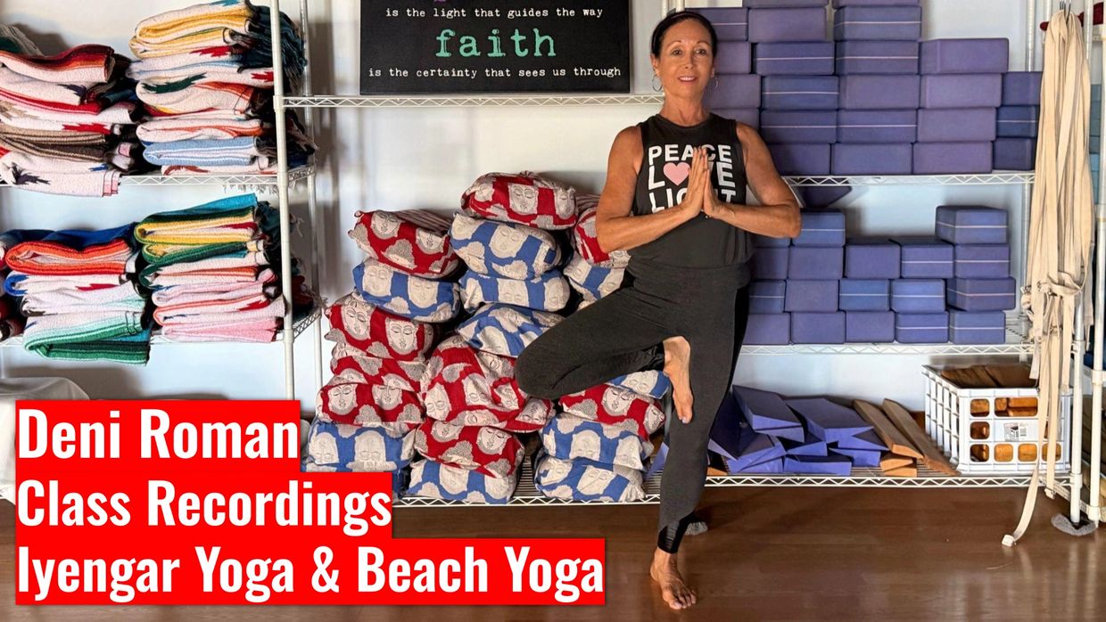 Woman practicing yoga tree pose in a studio with yoga props and blankets.