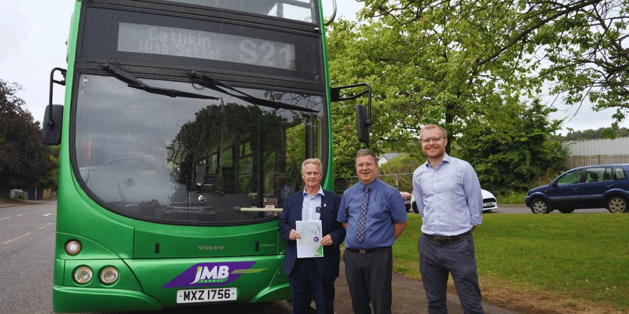 Three men standing in front of a green bus.