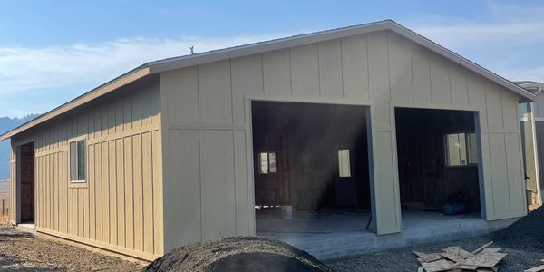 A partially constructed garage with an open front and beige siding.