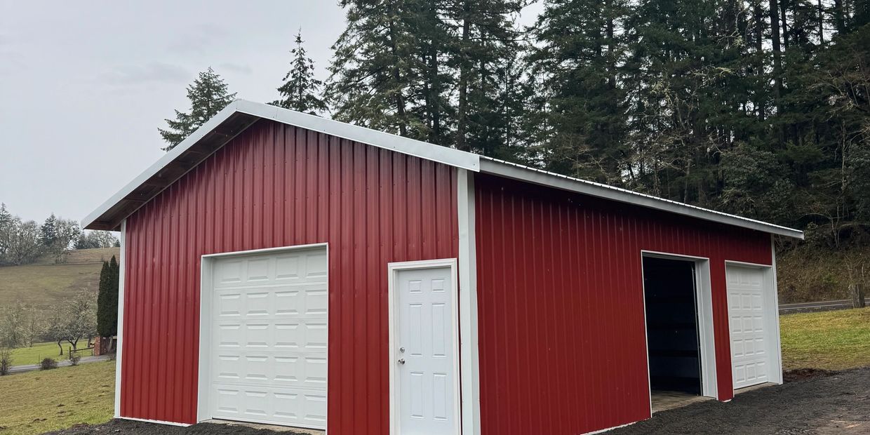 A red metal barn with white doors in a rural setting.