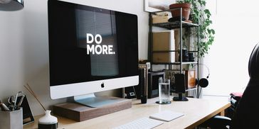 Modern workspace with a motivational 'DO MORE.' message on the computer screen.