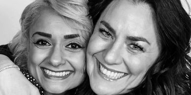 Two women smiling closely together for a candid photo.